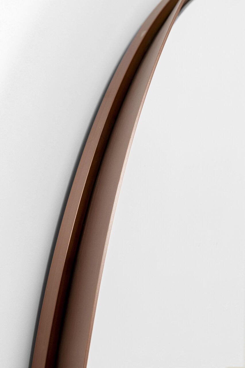 Close-up van een wandspiegel met een elegante, bruine lijst, gezien vanaf de zijkant.