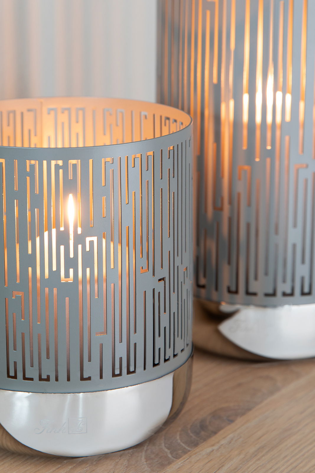 Windlicht mit modernem, geometrischem Muster, beleuchtet von einer Kerze, aus seitlicher Perspektive fotografiert.