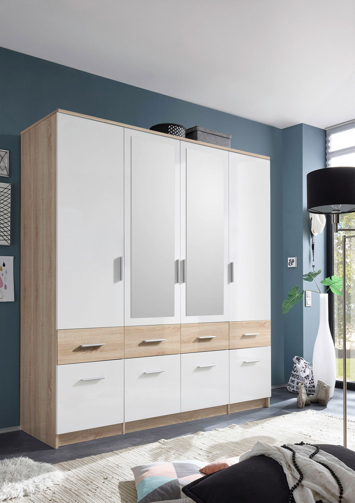 Moderner 4-türiger Drehtürenschrank mit Spiegeln und Schubladen, aus Holz und weißem Material, in einem stilvollen Raum von vorne betrachtet.