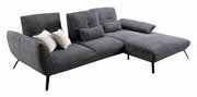 Graues Ecksofa mit Rillenstruktur, zwei weißen und zwei grauen Kissen, aus seitlicher Perspektive fotografiert.