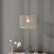 Moderne Pendelleuchte mit beigem, zylindrischem Lamellenschirm und sichtbarer Glühbirne, frontale Ansicht vor grauer Wand über einem Tisch mit Vase und Deko
