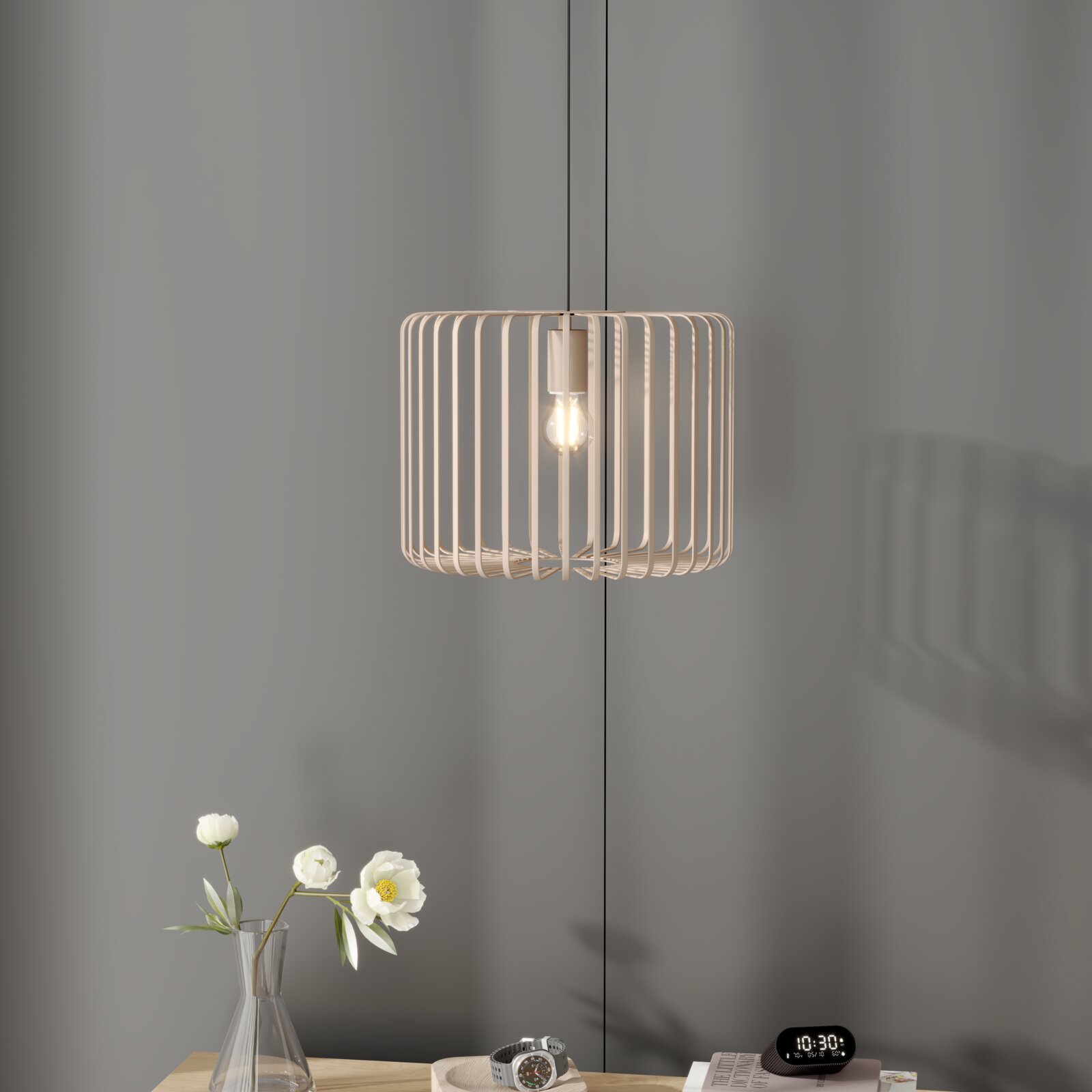 Moderne Pendelleuchte mit beigem, zylindrischem Lamellenschirm und sichtbarer Glühbirne, frontale Ansicht vor grauer Wand über einem Tisch mit Vase und Deko
