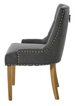 Seitenansicht eines eleganten grauen Stuhls mit Nietenverzierung und Holzbeinen.