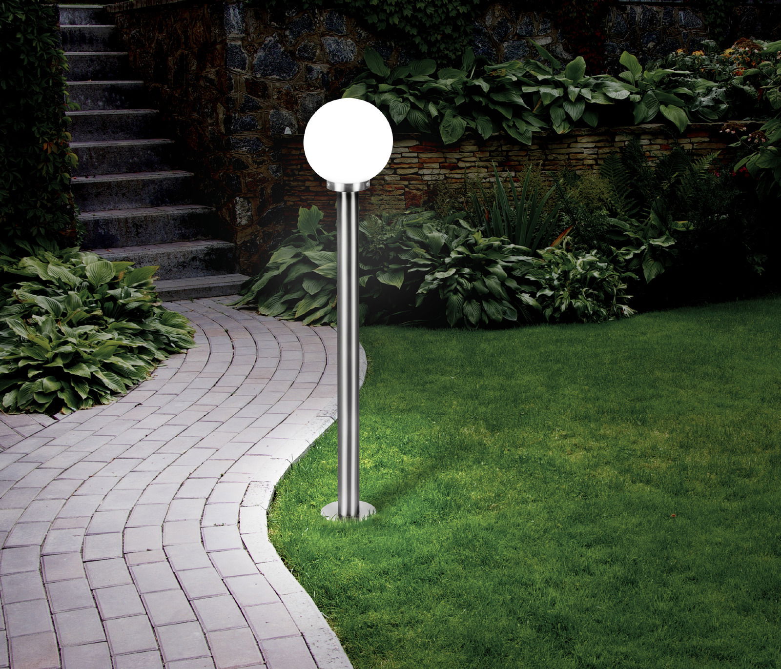 Außen-Stehleuchte NISIA im Garten, seitliche Perspektive, mit rundem Leuchtkopf auf einem schlanken, silbernen Stab.