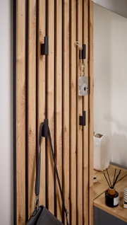 Nahaufnahme einer Kompaktgarderobe mit Holzlatten und schwarzen Haken, an denen eine Kamera und eine Tasche hängen. Perspektive von der Seite.