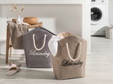 Zwei Wäschesäcke mit der Aufschrift 'Laundry' in einem modernen Waschraum, einer in Grau und einer in Beige, mit Seilgriffen, aus der Vorderansicht fotografiert.