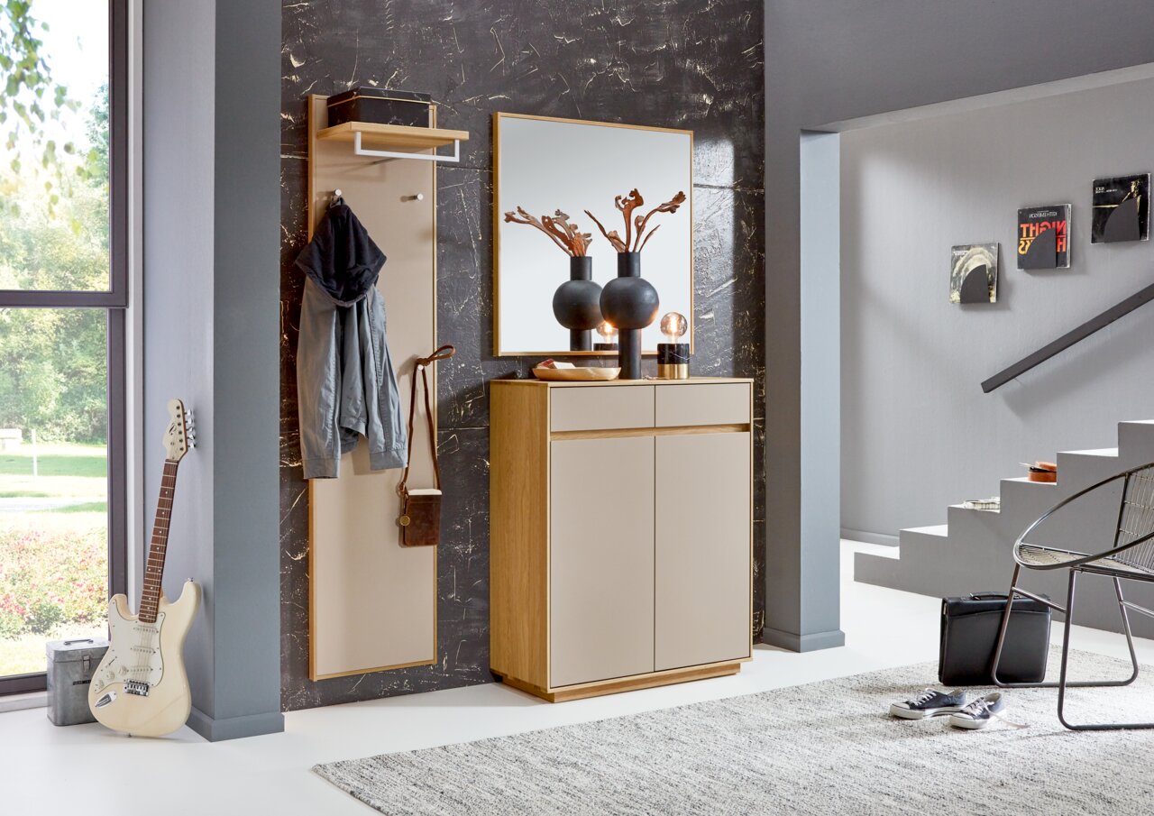 Moderner Eingangsbereich mit Garderobenpaneel, Spiegel und Kommode in Holzoptik, seitliche Perspektive.