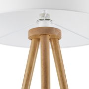 Nahaufnahme einer Stehleuchte mit dreibeinigem Holzgestell und weißem Lampenschirm, von unten betrachtet.