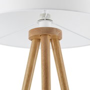 Nahaufnahme einer Stehleuchte mit dreibeinigem Holzgestell und weißem Lampenschirm, von unten betrachtet.
