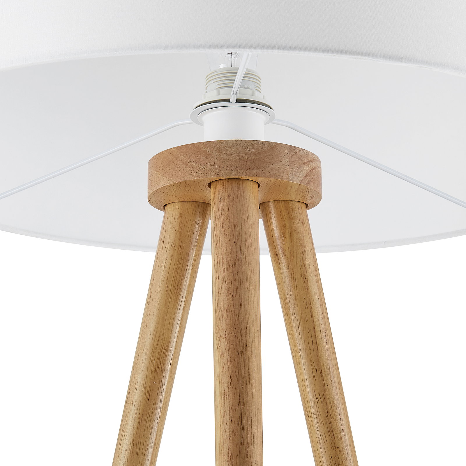Close-up van een staande lamp met een houten driepoot en een witte lampenkap, gezien van onderaf.