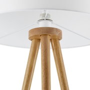 Nahaufnahme einer Stehleuchte mit dreibeinigem Holzgestell und weißem Lampenschirm, von unten betrachtet.