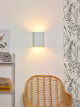 Moderne Wandleuchte in minimalistischem Design, die warmes Licht nach oben und unten abstrahlt, seitliche Perspektive.
