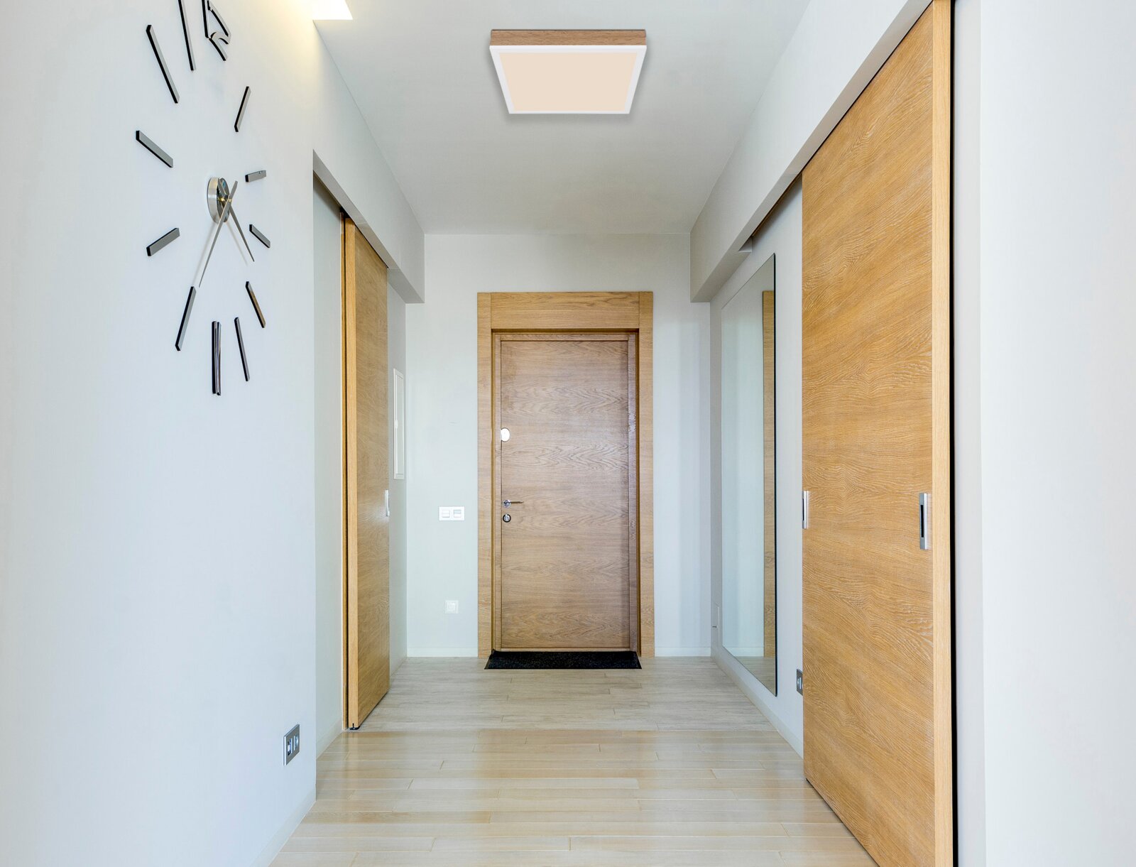 Moderne Deckenleuchte in einem Flur mit Holztüren und Wanduhr, von unten betrachtet.