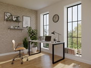 Modernes Homeoffice mit weißem Schreibtisch und schwarzem Metallgestell, Schreibtischlampe, Laptop, Rollstuhl und Pflanzen vor Ziegelwand und großen Fenstern, Perspektive: leicht schräg von vorne aus Augenhöhe.