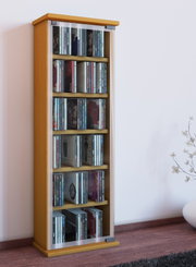 Schmaler CD-/DVD-Turm aus hellem Holz mit Glastür und mehreren Regalböden, gefüllt mit CDs, in leichter Schrägansicht von vorn links vor einer weißen Wand.