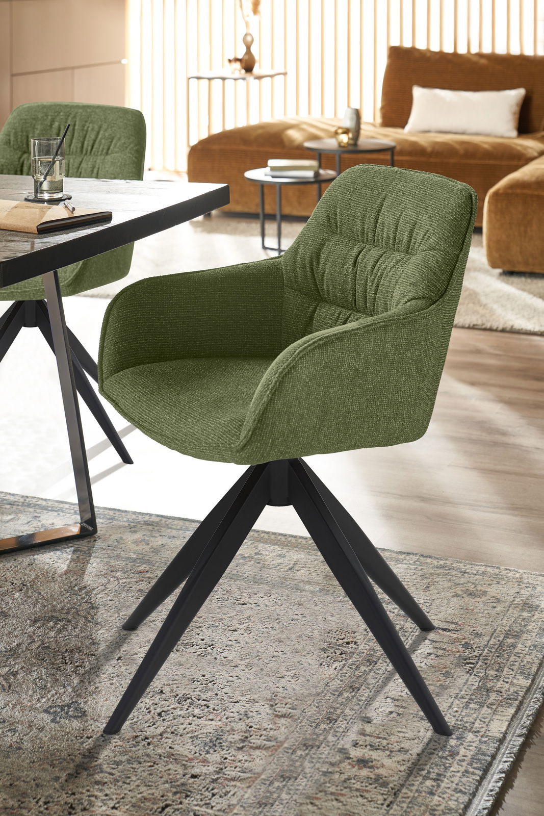Grüner Armlehnstuhl mit schwarzem Metallgestell, seitliche Perspektive
