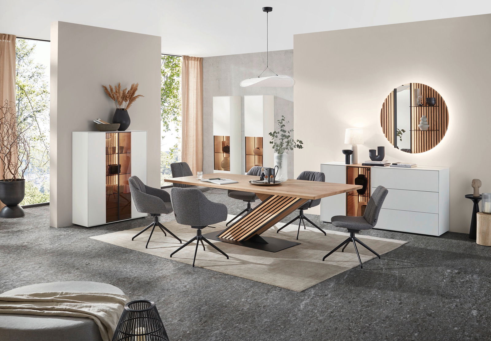 Moderne Esszimmer-Einrichtung mit Esstisch aus Holz, umgeben von grauen Stühlen, und weißen Vitrinen im Hintergrund. Perspektive: Frontalansicht.