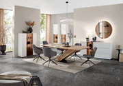 Moderne eetkamerinrichting met een houten eettafel, omringd door grijze stoelen, en witte vitrinekasten op de achtergrond. Perspectief: vooraanzicht.