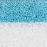 Nahaufnahme eines zweischichtigen Matratzentoppers mit einer weißen und einer blauen Schicht, seitliche Perspektive.