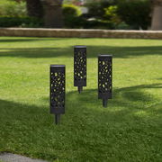 Drei schwarze Solarleuchten mit dekorativem Muster, aufrecht im grünen Rasen stehend, aus seitlicher Perspektive fotografiert.