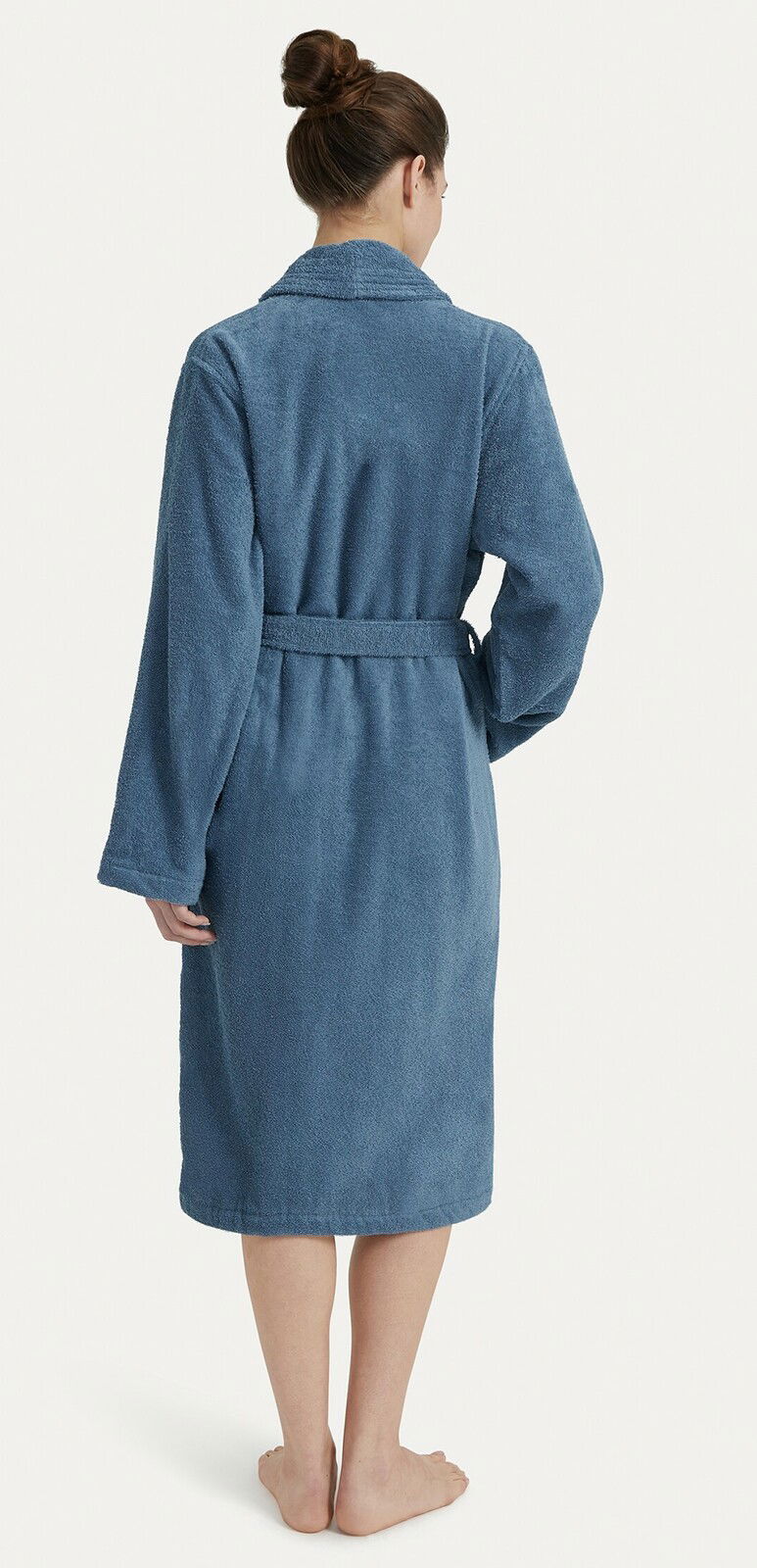 Rückansicht eines blauen Bademantels mit Schalkragen, getragen von einer Person. Der Bademantel hat einen Gürtel und reicht bis zu den Waden.
