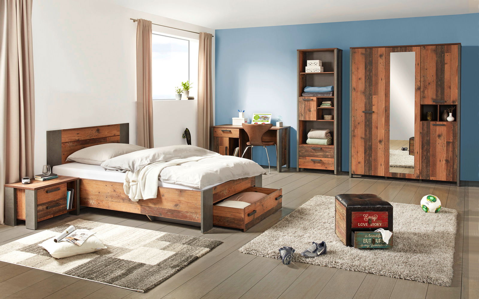 Schlafzimmermöbel-Set in moderner Holzoptik, bestehend aus einem Bett mit Unterbettschubkasten, einer Nachtkommode, einem Regal, einem Schreibtisch und einem dreitürigen Drehtürenschrank mit Spiegel. Perspektive: Frontalansicht des gesamten Sets in einem