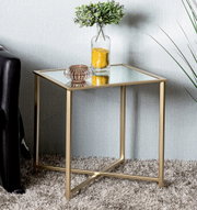 Quadratischer Beistelltisch mit goldfarbenem Metallgestell und Glasplatte, seitliche Perspektive im Wohnzimmer neben Sofa, dekoriert mit Vase und Schale