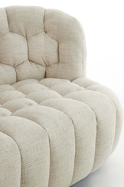 Nahaufnahme einer beigen Couch mit gepolstertem, gestepptem Design, seitliche Perspektive