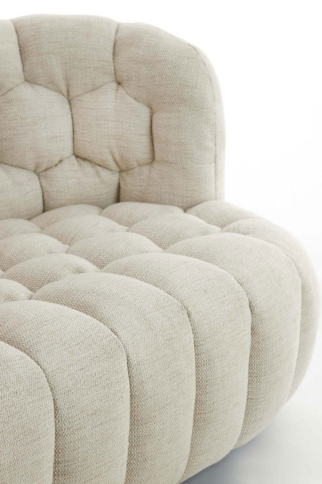 Nahaufnahme einer beigen Couch mit gepolstertem, gestepptem Design, seitliche Perspektive