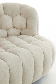 Nahaufnahme einer beigen Couch mit gepolstertem, gestepptem Design, seitliche Perspektive