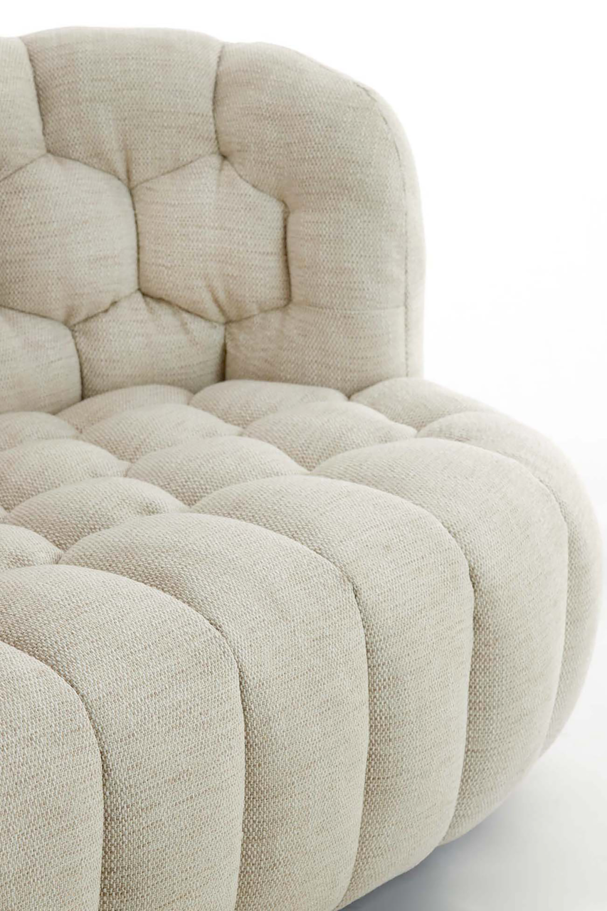 Nahaufnahme einer beigen Couch mit gepolstertem, gestepptem Design, seitliche Perspektive