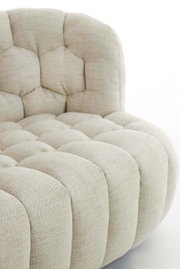 Nahaufnahme einer beigen Couch mit gepolstertem, gestepptem Design, seitliche Perspektive
