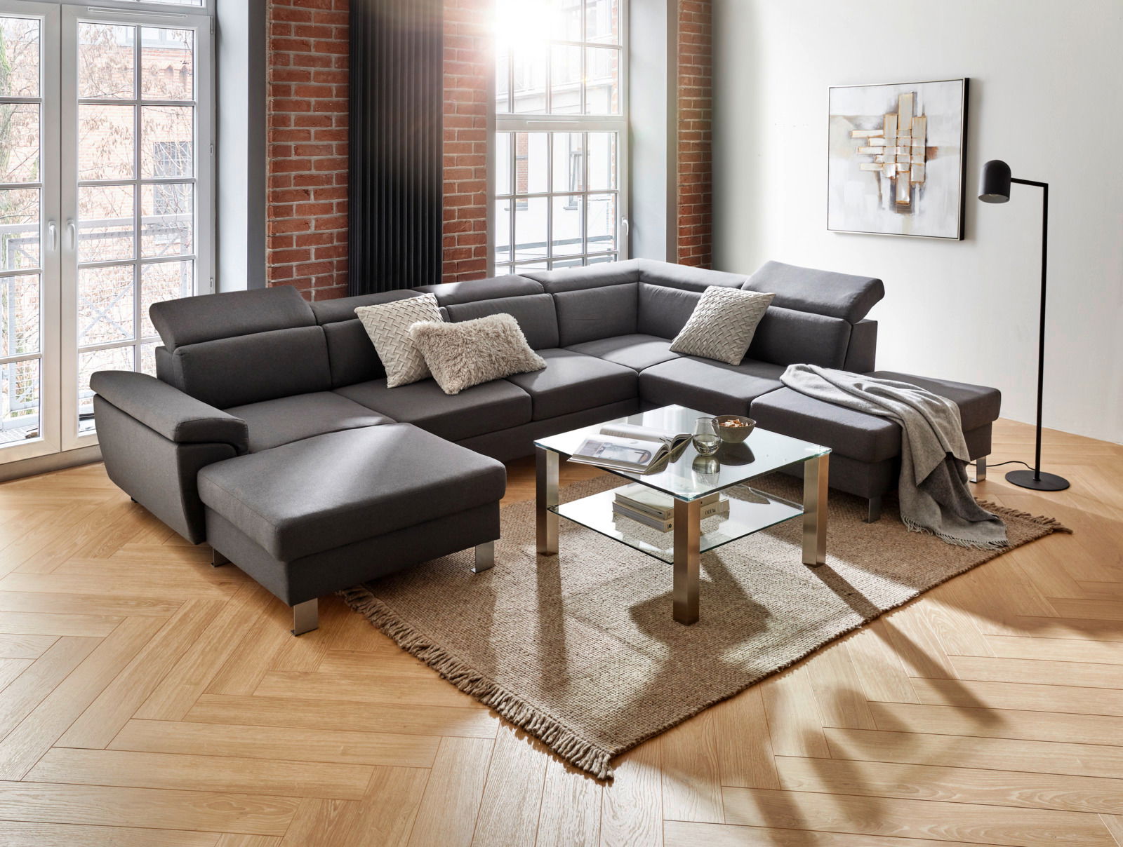 Moderne graue Rundecke in einem stilvollen Wohnzimmer mit großen Fenstern, Holzboden und dekorativen Kissen, aus der Perspektive von vorne links.