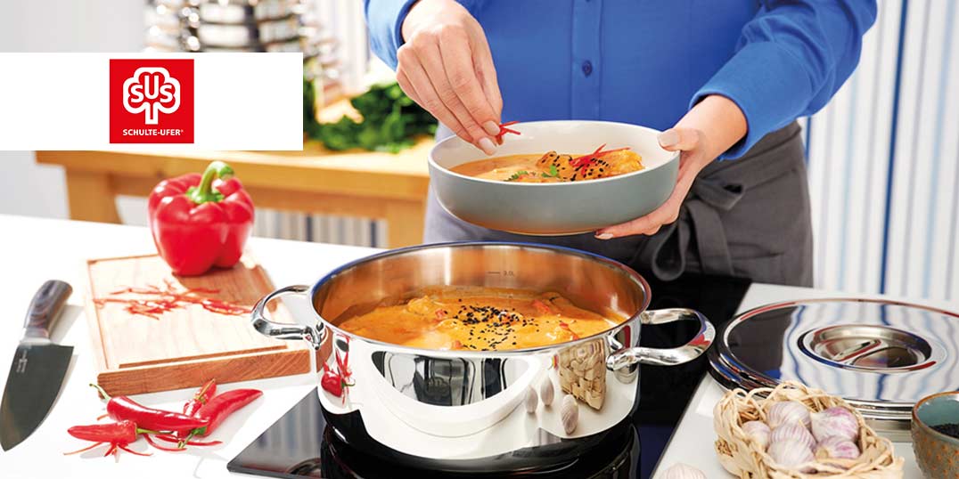 Person serviert Suppe aus Schulte-Ufer Edelstahltopf, frische Zutaten auf dem Schneidebrett.