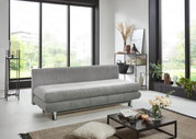 Graues Funktionssofa in modernem Wohnzimmer, seitliche Perspektive mit großen Fenstern im Hintergrund.