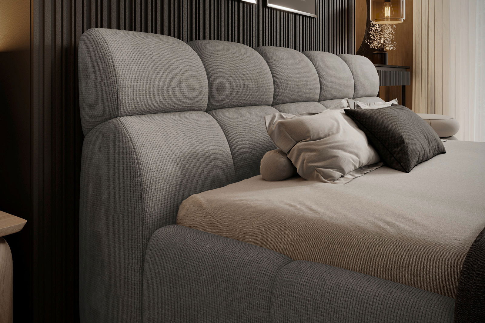 Seitliche Perspektive auf ein graues Polsterbettgestell mit mehreren Kissen auf dem Bett.