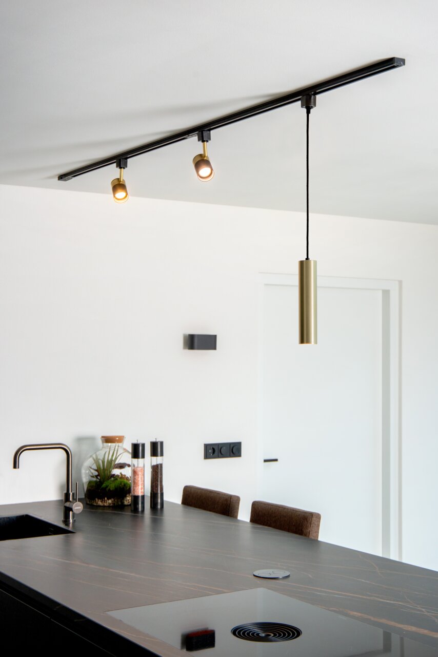 Moderne Pendelleuchte FLORIS in mattgoldener Ausführung, von der Decke hängend über einer Kücheninsel, seitliche Perspektive.