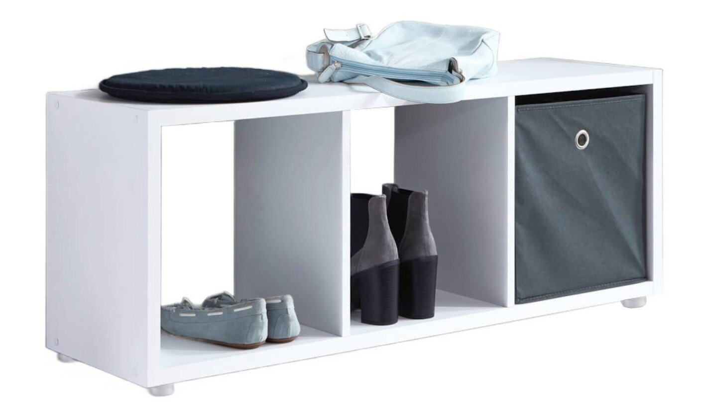 Weißes Schuhregal/Schuhbank mit drei Fächern und grauer Stoffbox, vorne schräg von links fotografiert; oben liegen Sitzkissen und Tasche, unten stehen Schuhe.