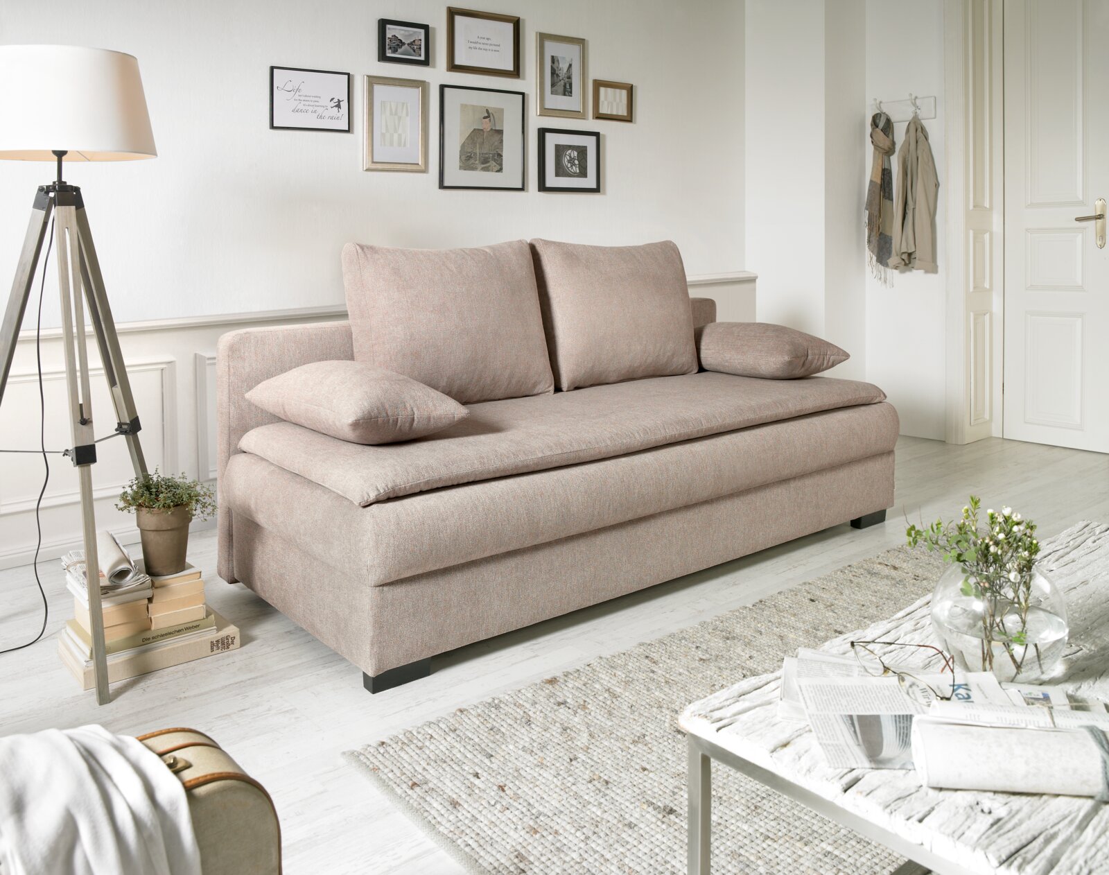 Beige functionele bank in een lichte woonkamer, gezien vanaf de zijkant, met kussens en decoratieve elementen.