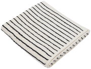 Gefaltetes Duschtuch mit schwarzen Streifen auf weißem Hintergrund, von schräg oben fotografiert.