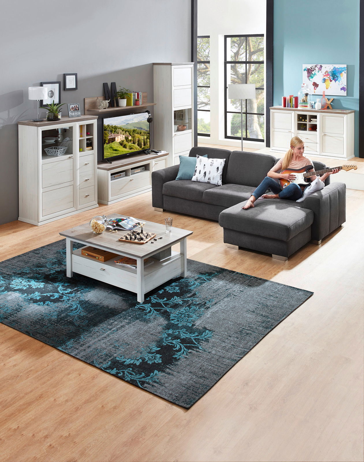 Wohnzimmer mit grauem Ecksofa, Couchtisch und Wohnwand in heller Holzoptik, seitliche Perspektive