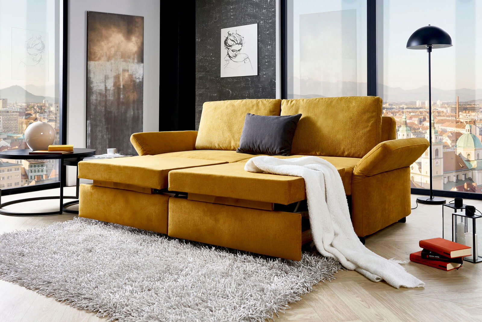 Gelbes Funktionssofa in einem modernen Wohnzimmer mit Stadtblick, von vorne betrachtet.