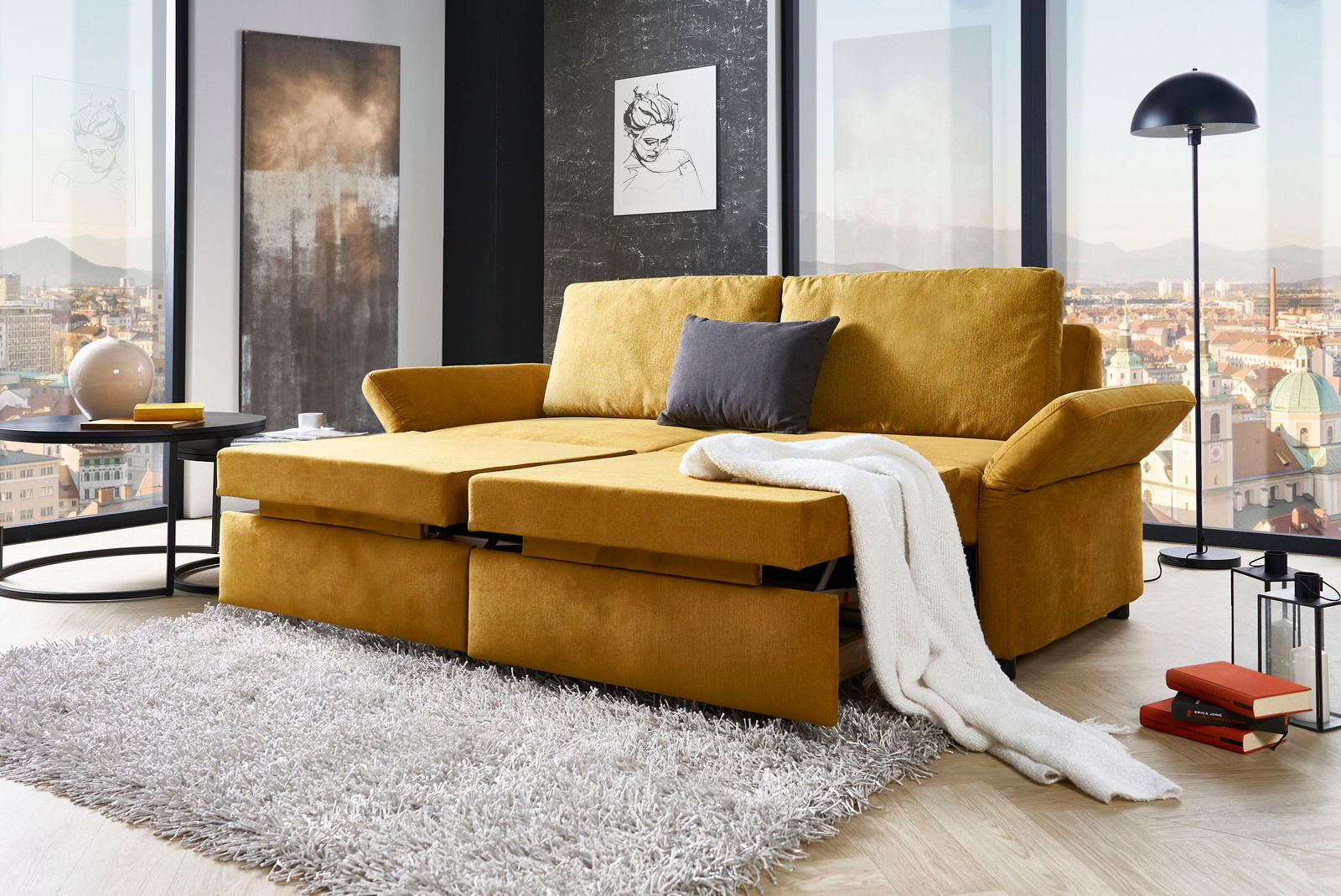 Gelbes Funktionssofa in einem modernen Wohnzimmer mit Stadtblick, von vorne betrachtet.