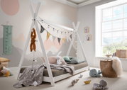 Tipibett aus weißem Holz mit dekorativen Lichterketten und Wimpeln, umgeben von Kuscheltieren und Spielzeug in einem hellen Kinderzimmer mit großem Fenster.