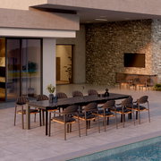 Moderner Außenbereich mit einem langen Esstisch und mehreren Loungestühlen, seitliche Perspektive.