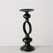 Schwarzer Kerzenleuchter Plokky aus Metall, frontal vor einer weißen Ziegelwand fotografiert.