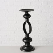 Zwarte metalen kandelaar Plokky, van voren gefotografeerd voor een witte bakstenen muur.