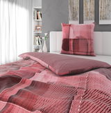 Wendebettwäsche in Rot- und Rosatönen mit geometrischem Muster auf einem Bett, seitliche Perspektive.