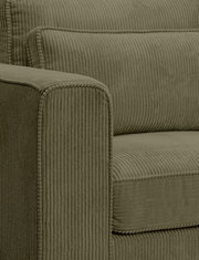 Nahaufnahme eines olivgrünen Cord-Sofas mit geripptem Bezug, sichtbarer Armlehne und Sitzpolster, fotografiert aus seitlicher Frontperspektive.