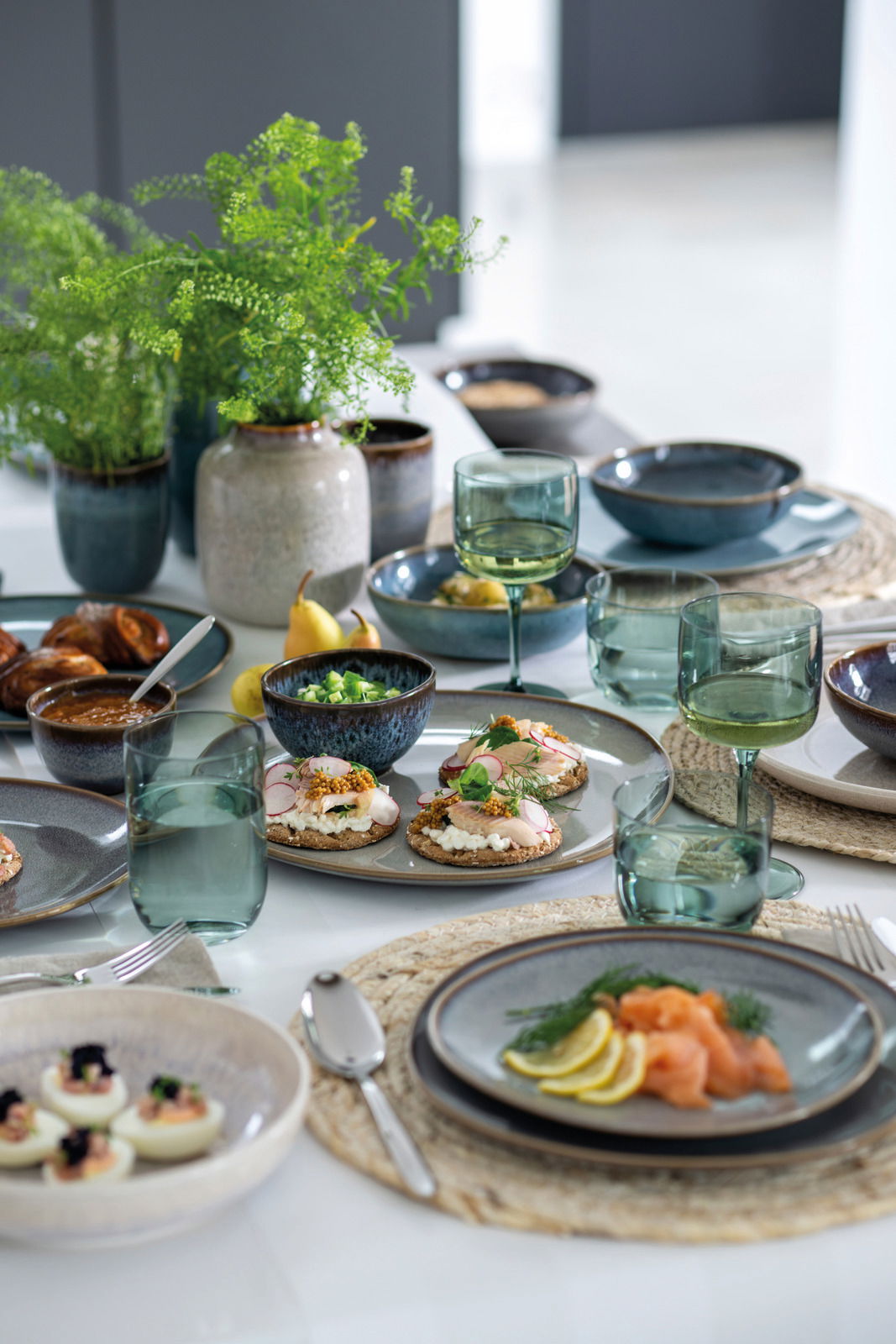 Elegantes Weinkelch-Set auf einem gedeckten Tisch mit verschiedenen Speisen, aus der Vogelperspektive fotografiert.